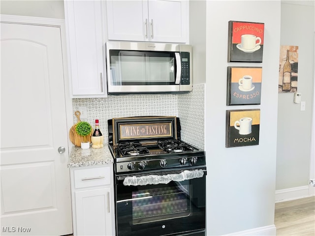 kitchen featuring light hardwood / wood-style flooring, backsplash, white cabinetry, light stone countertops, and gas stove