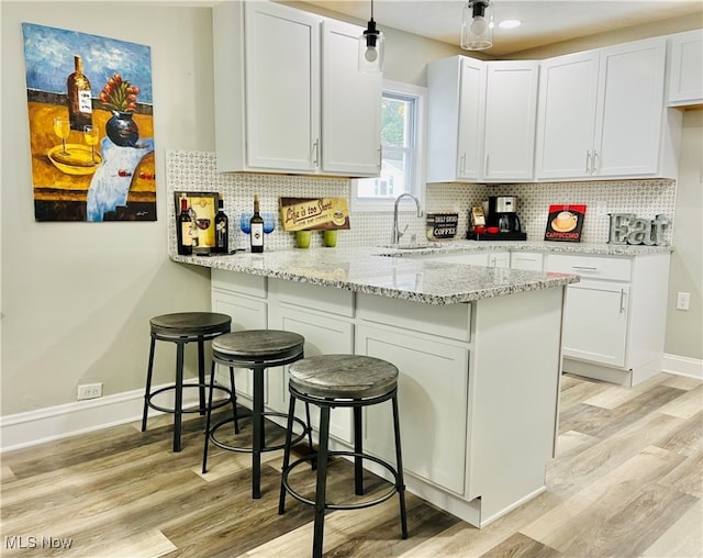 kitchen with a breakfast bar, sink, kitchen peninsula, and white cabinets