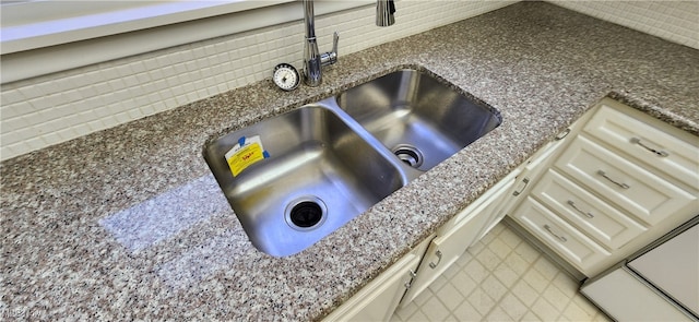 interior details featuring dark stone countertops, cream cabinets, sink, and tasteful backsplash