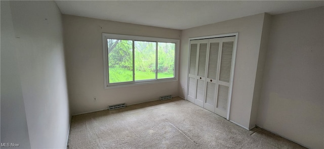 unfurnished bedroom with light carpet and a closet