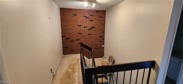 stairs with carpet flooring and brick wall