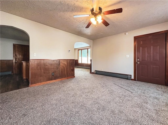 empty room with a baseboard heating unit, a textured ceiling, and carpet