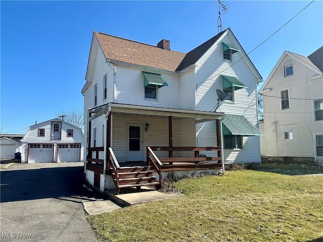 view of front of home with a shingled roof, a chimney, a detached garage, a porch, and a front yard