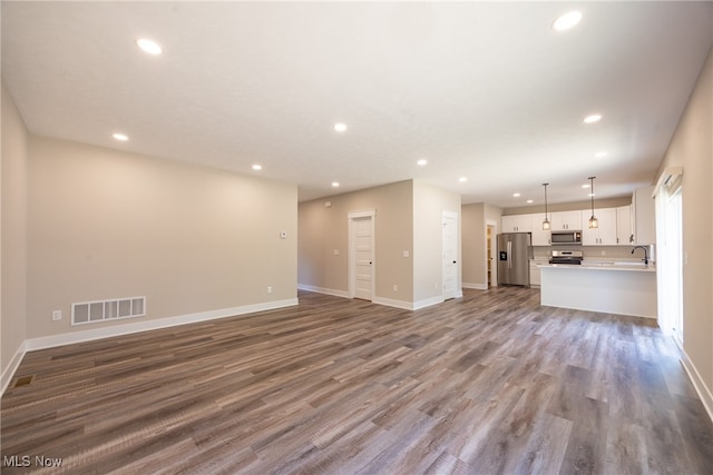 unfurnished living room featuring sink and hardwood / wood-style flooring