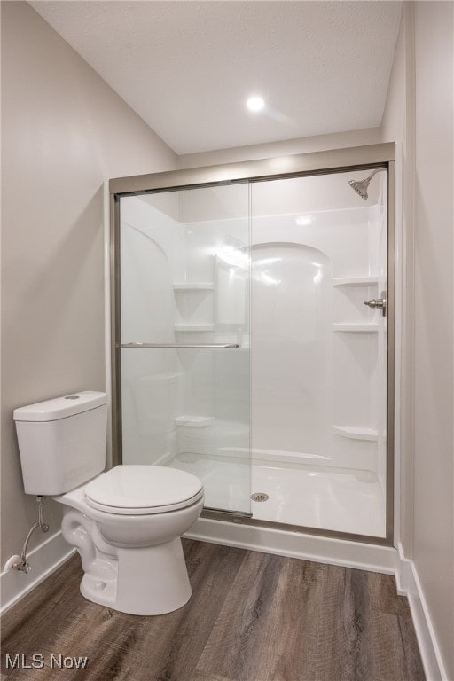 bathroom featuring walk in shower, hardwood / wood-style floors, and toilet