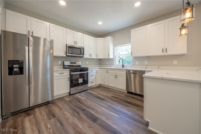 kitchen with pendant lighting, light stone counters, dark hardwood / wood-style floors, white cabinetry, and appliances with stainless steel finishes