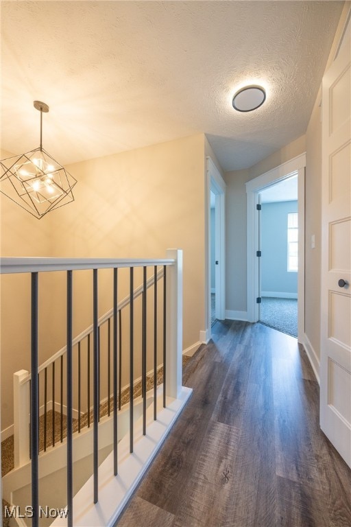 hallway featuring an inviting chandelier, dark hardwood / wood-style floors, and a textured ceiling