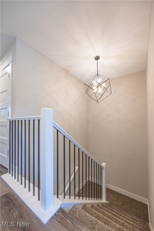 stairway with a chandelier and hardwood / wood-style flooring