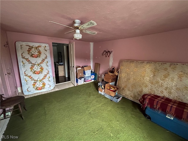 bedroom with ceiling fan, carpet floors, and a textured ceiling