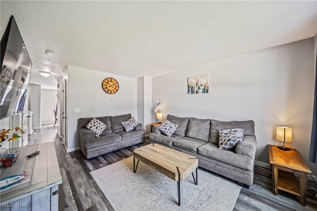 living room with a textured ceiling and dark hardwood / wood-style floors