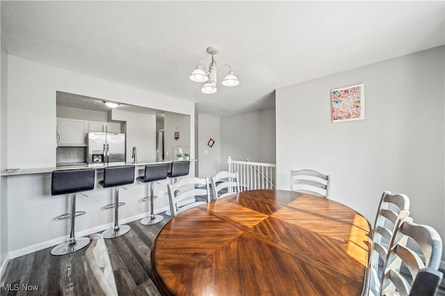 dining room with wood-type flooring, sink, and a notable chandelier