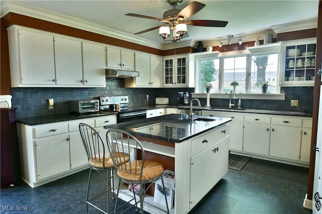 kitchen featuring ceiling fan, an island with sink, sink, white cabinetry, and electric range