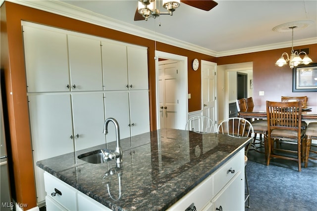 kitchen featuring pendant lighting, ornamental molding, sink, white cabinetry, and ceiling fan with notable chandelier