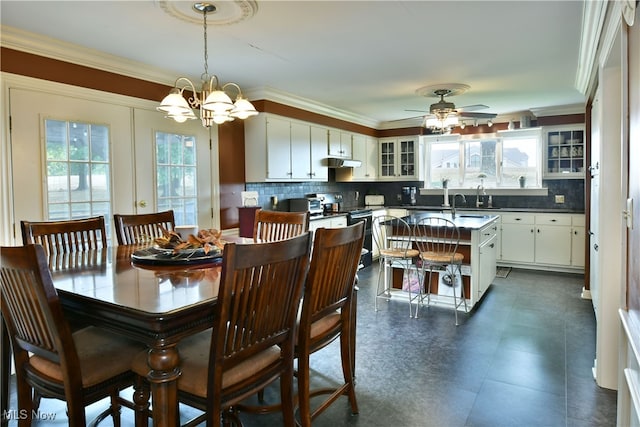 dining space featuring ceiling fan with notable chandelier, crown molding, sink, and a healthy amount of sunlight