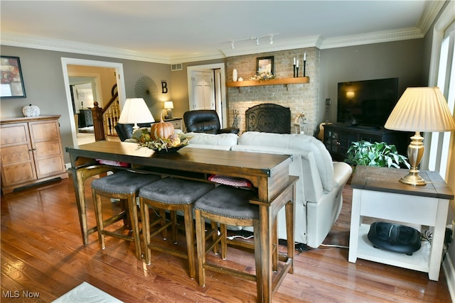 interior space featuring wood-type flooring, rail lighting, a fireplace, and crown molding