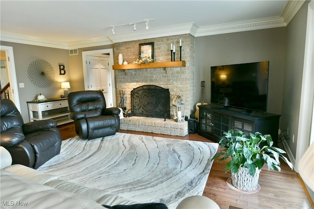 living room featuring crown molding, hardwood / wood-style floors, and a brick fireplace