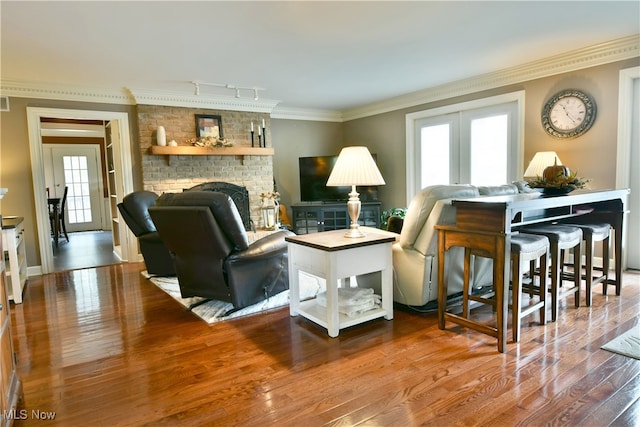 living room featuring hardwood / wood-style flooring, a fireplace, ornamental molding, and a wealth of natural light