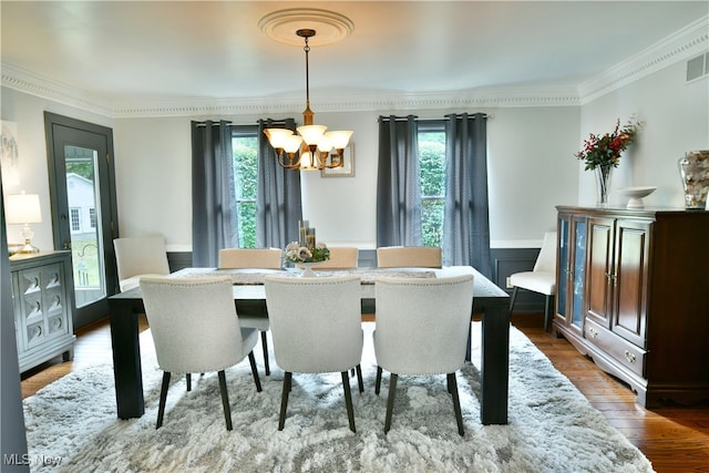 dining space featuring an inviting chandelier, crown molding, hardwood / wood-style flooring, and a wealth of natural light