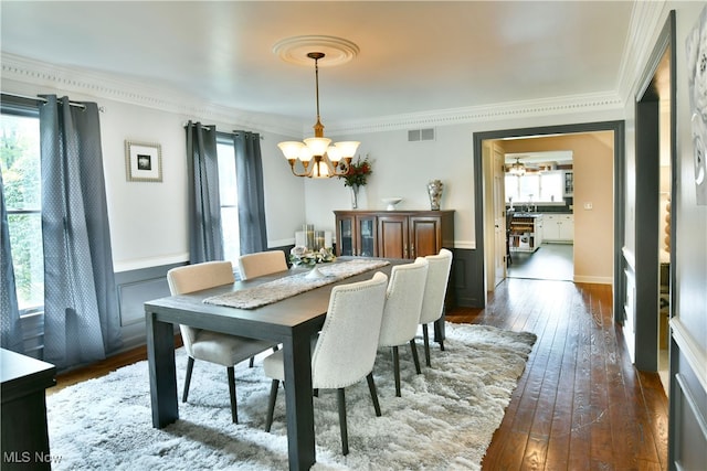 dining area with ornamental molding, dark hardwood / wood-style flooring, and a notable chandelier