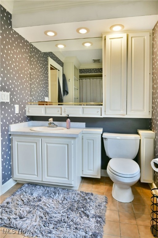 bathroom with crown molding, vanity, toilet, and tile patterned floors