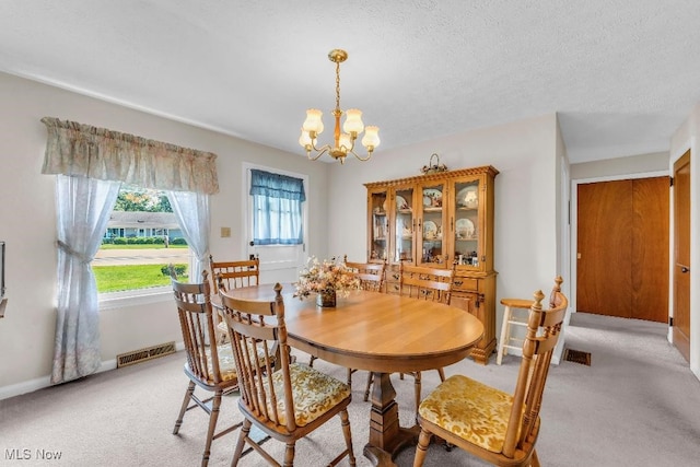 dining space with a textured ceiling, light colored carpet, and an inviting chandelier