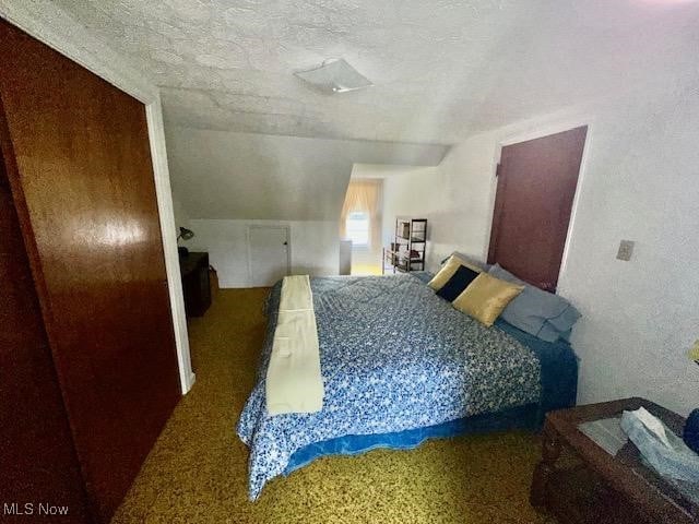 carpeted bedroom with a textured ceiling and lofted ceiling