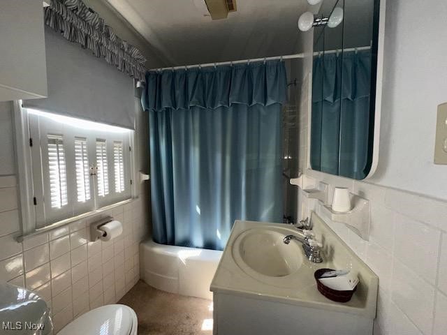 full bathroom with shower / bath combo, toilet, tile walls, and vanity