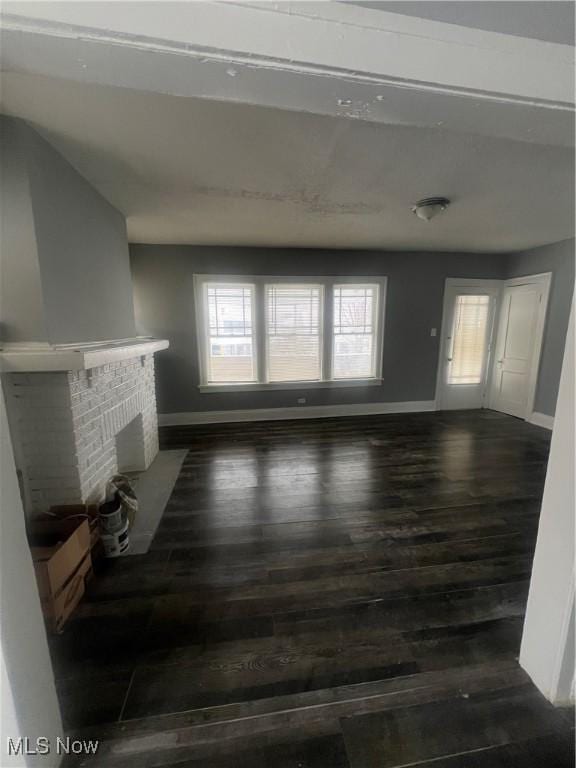 unfurnished living room featuring a fireplace and dark hardwood / wood-style floors