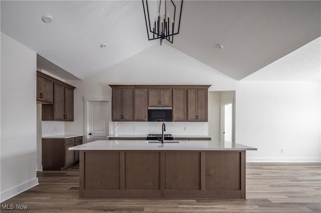 kitchen with tasteful backsplash, lofted ceiling, and a center island with sink