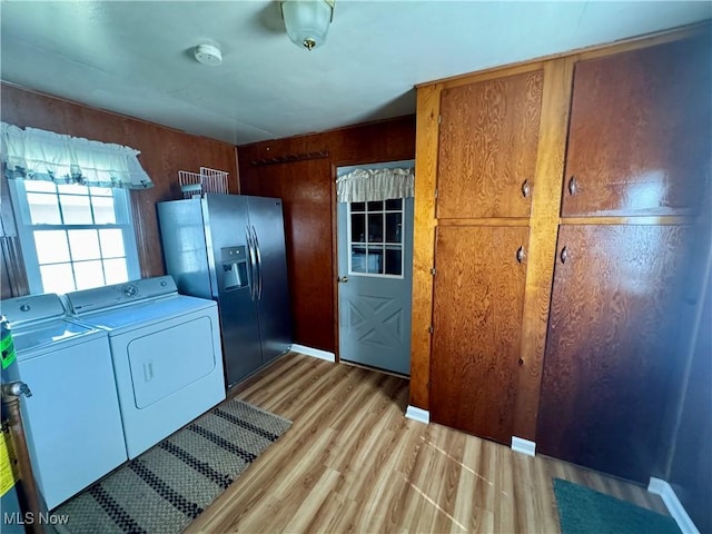 washroom featuring wood walls, cabinets, light wood-type flooring, and washing machine and dryer