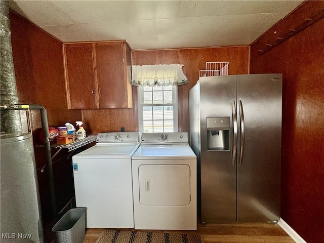 laundry room featuring cabinets, washing machine and dryer, hardwood / wood-style floors, and wooden walls