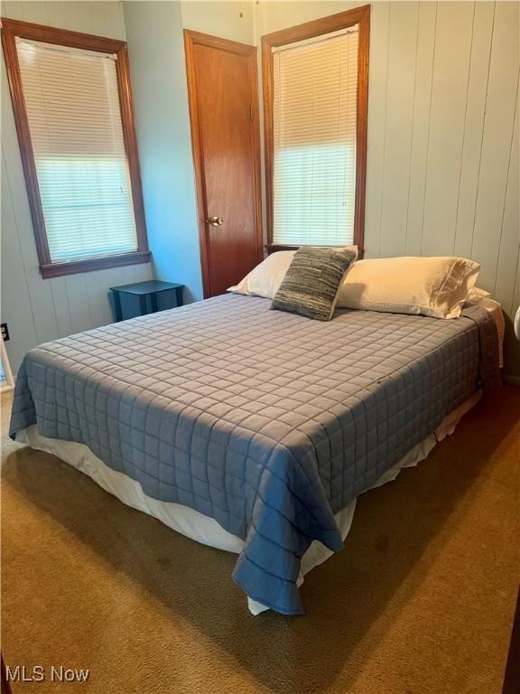 bedroom with carpet flooring and wooden walls