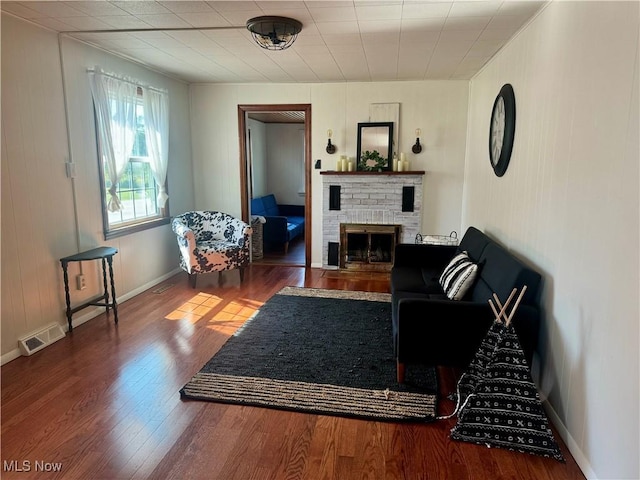 living room featuring hardwood / wood-style flooring and a brick fireplace