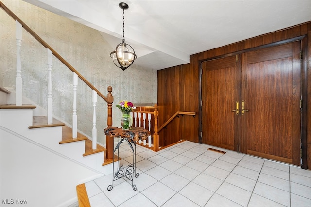 tiled foyer entrance with a notable chandelier and wooden walls