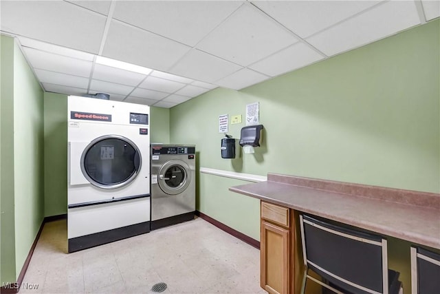 clothes washing area featuring light floors, baseboards, and washing machine and clothes dryer