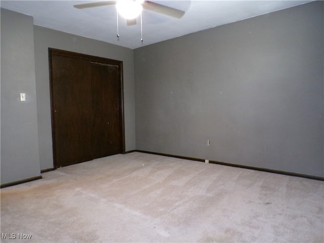 unfurnished bedroom featuring ceiling fan, a closet, and light colored carpet