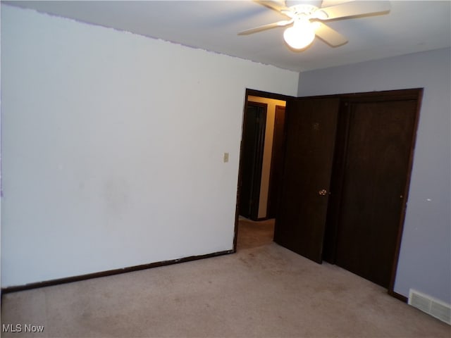 unfurnished bedroom with ceiling fan, light carpet, and a closet