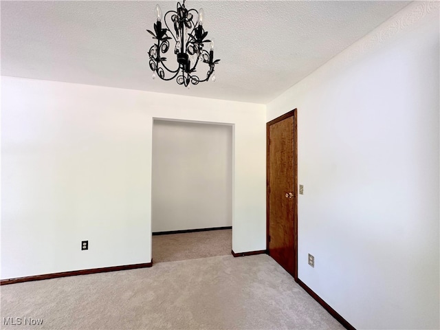 interior space featuring light colored carpet, an inviting chandelier, and a textured ceiling