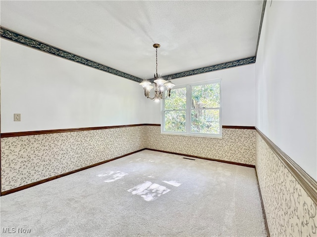 empty room with a chandelier, a textured ceiling, and carpet floors