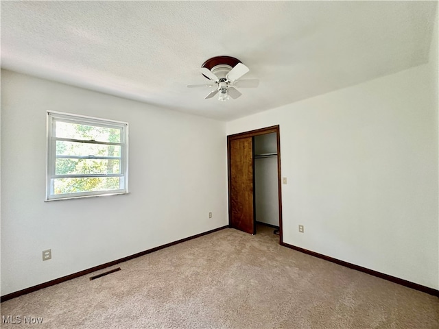 carpeted empty room featuring ceiling fan and a textured ceiling