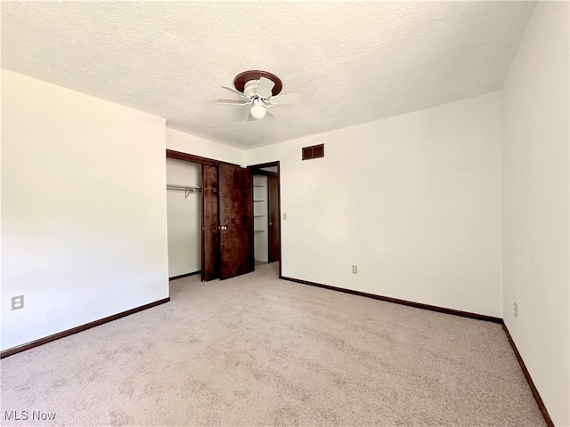 unfurnished bedroom with ceiling fan, light colored carpet, a textured ceiling, and a closet