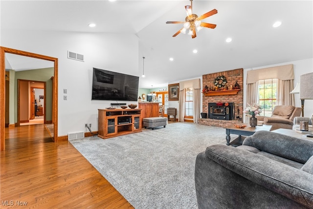 living room featuring a wood stove, ceiling fan, hardwood / wood-style floors, and high vaulted ceiling