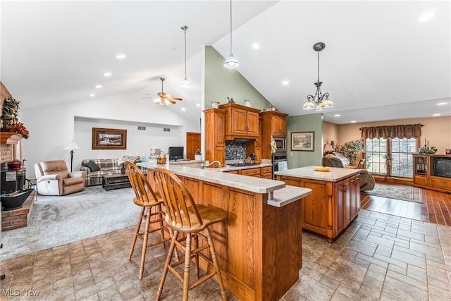 kitchen with a kitchen breakfast bar, a spacious island, light colored carpet, pendant lighting, and ceiling fan with notable chandelier