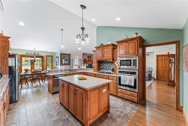 kitchen featuring kitchen peninsula, pendant lighting, stainless steel appliances, and an inviting chandelier