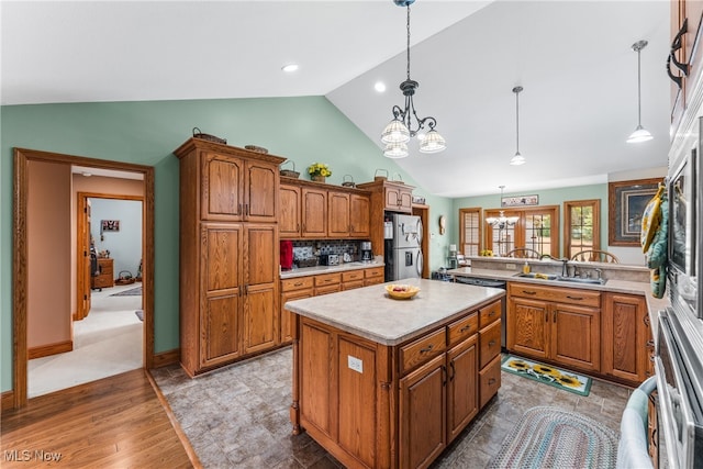 kitchen featuring lofted ceiling, sink, hanging light fixtures, a notable chandelier, and a kitchen island