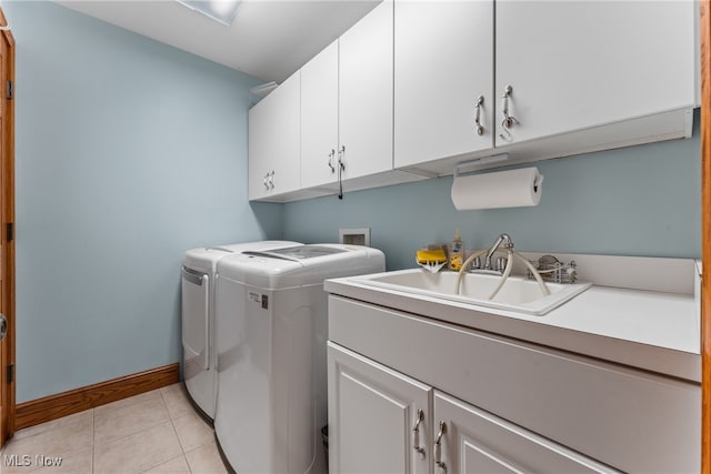 laundry room featuring cabinets, light tile patterned floors, sink, and washing machine and clothes dryer