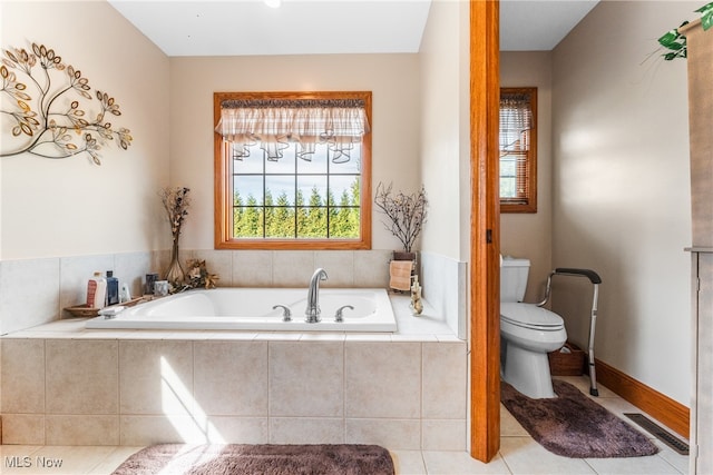 bathroom featuring tile patterned flooring, a relaxing tiled tub, and toilet