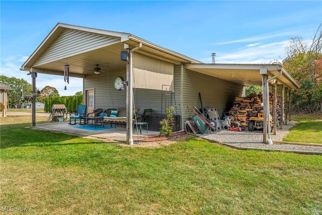 rear view of property with ceiling fan, a patio area, and a lawn