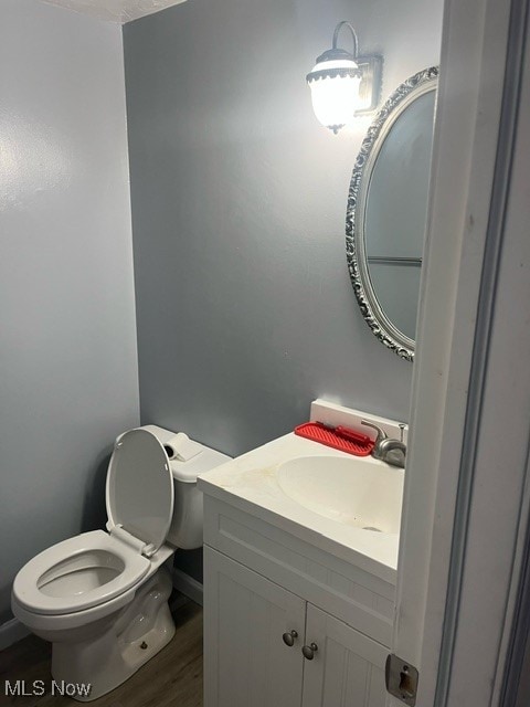 bathroom with vanity, toilet, and hardwood / wood-style flooring