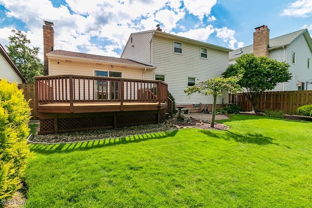 back of property with a wooden deck and a lawn